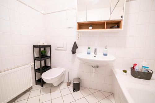 a white bathroom with a toilet and a sink at FULL HOUSE Premium Apartments Magdeburg E3 in Magdeburg