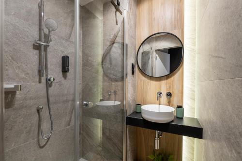 La salle de bains est pourvue d'une douche, d'un lavabo et d'un miroir. dans l'établissement Luxury Copper Apartment II, à Łódź