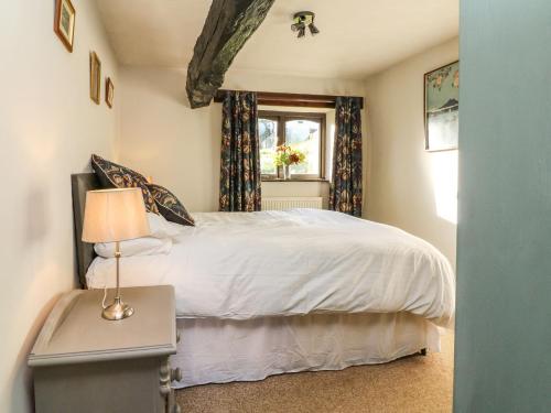 a bedroom with a white bed and a window at Bracken Cottage in Okehampton