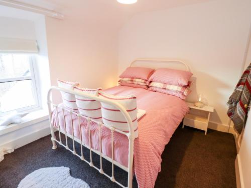 a bedroom with a bed with pink sheets and pillows at 1 Llwyn Hir in Blaenau-Ffestiniog