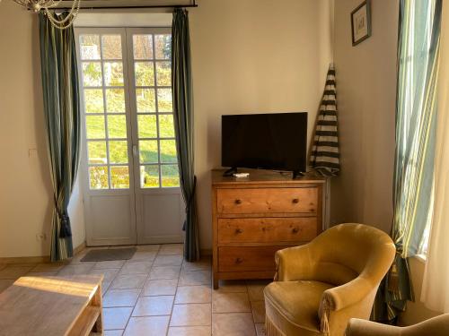 a living room with a tv and a chair and a dresser at La Manufacture Royale de Bains in Bains-les-Bains