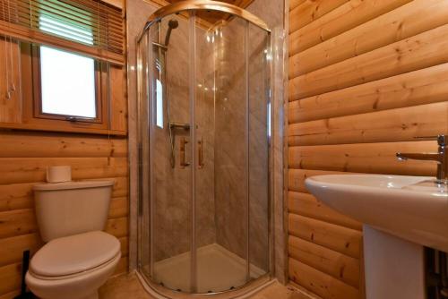 a bathroom with a shower and a toilet and a sink at Heather Cottages - Grey Heron in Bamburgh