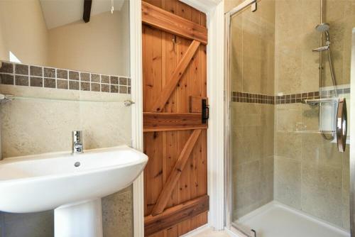 een badkamer met een wastafel en een douche met een deur bij Goldfinch in Lucker