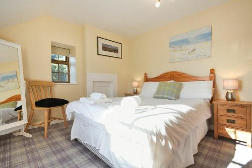 een slaapkamer met een groot wit bed en een stoel bij Heather Cottages - Godwit in Bamburgh