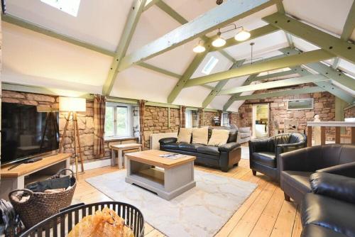 a living room with leather furniture and a stone wall at Millstone in Lucker