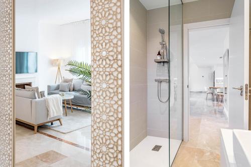 ein Badezimmer mit einer Glasdusche und ein Wohnzimmer in der Unterkunft PA18- El Paraiso Estepona by Roomservices in Estepona
