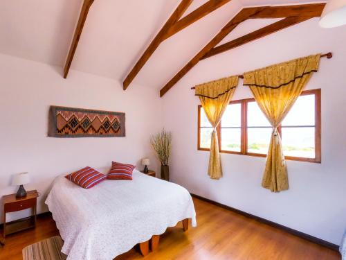 1 dormitorio con 1 cama y 2 ventanas en La Chakana Lodge, en Putre