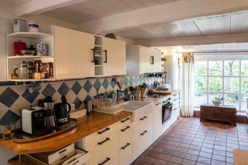 a kitchen with white cabinets and a large window at Ferienhaus Strandgut in Oevenum