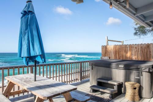 哈萊伊瓦的住宿－Hawaii Oceanfront Beach House Paradise on the Beach Family Activities，海洋甲板上的遮阳伞和野餐桌