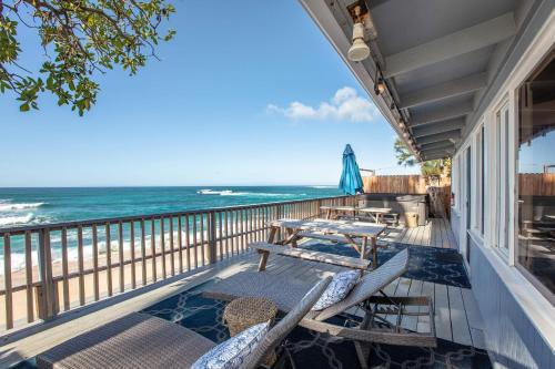 einen Balkon mit Stühlen, Tischen und Meerblick in der Unterkunft Hawaii Oceanfront Beach House Paradise on the Beach Family Activities in Haleiwa