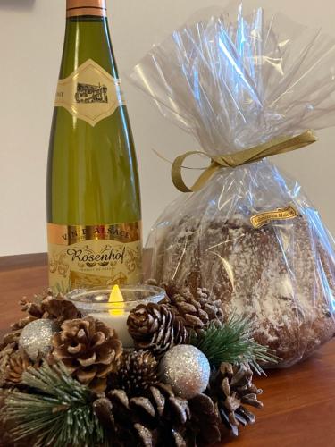- une bouteille de vin et une pièce maîtresse de Noël avec des cônes de pin dans l'établissement Gîte du Hibou - jolie dépendance sur verger, à Muhlbach-sur-Munster