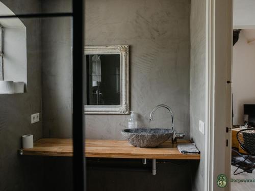 uma casa de banho com um lavatório de pedra e um espelho. em de Zeelberg em Valkenswaard