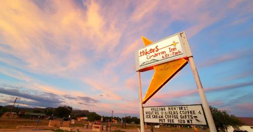 a sign for a black chicken run with a sky at Hikers Cimarron Inn & RV Park in Cimarron