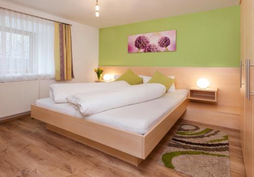 a bedroom with a bed with white sheets and green walls at Roslerhof in Inzing