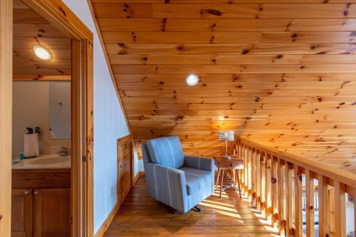 a staircase in a log house with a blue chair at Leafy Way Lodge in Linville Falls