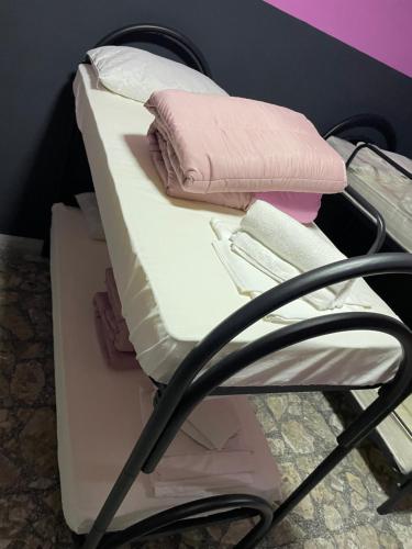 a bed with pink and white sheets and pillows on it at Alexander hostel in Naples