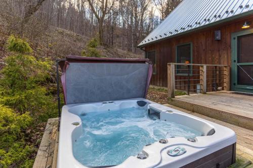 a jacuzzi tub sitting on a deck next to a cabin at A River Mist Walk in Sugar Grove