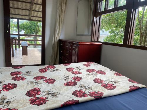 a bed with a blanket with red flowers on it at Pousada Happy in São Francisco do Sul