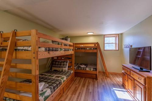 a bedroom with two bunk beds and a tv at Pine Creek Cabin in Blowing Rock