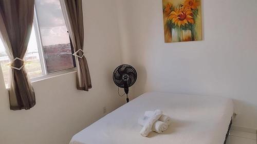 a white bedroom with a fan and a window at Apartamento aconchegante Parnamirim Natal in Parnamirim