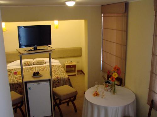 a room with a bed with a tv and two tables at Hotel Melodia in Lima