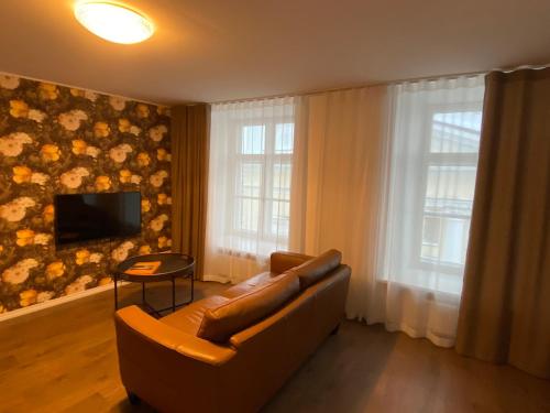 a living room with a leather couch and a television at Roofs of the Old Tallinn Guest House in Tallinn