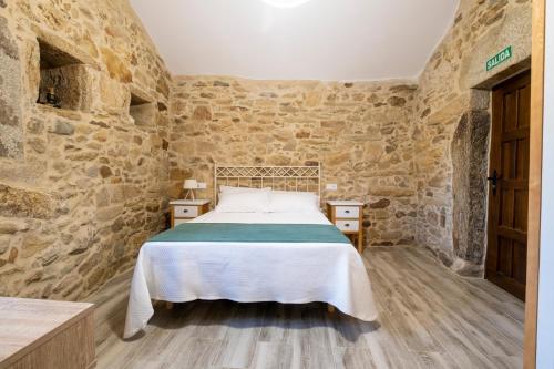 a bedroom with a bed in a stone wall at Casa Rural Laxido in Rianjo