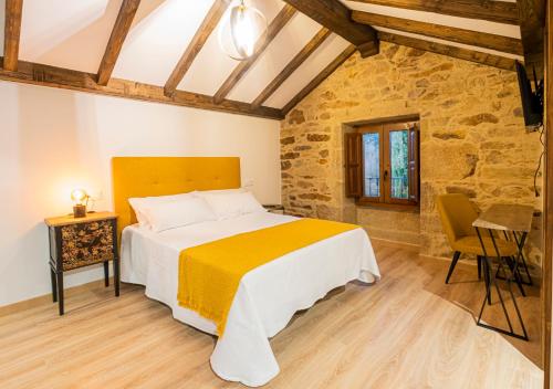 a bedroom with a bed with a yellow and white blanket at Casa Rural Laxido in Rianjo