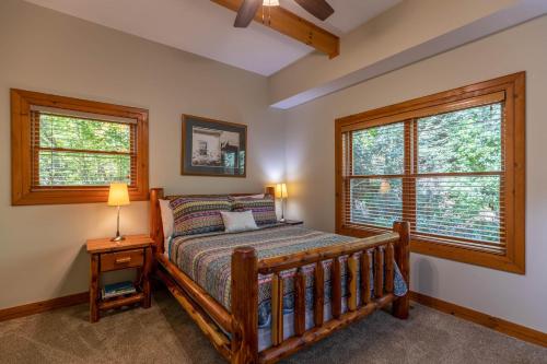 1 Schlafzimmer mit einem Holzbett und 2 Fenstern in der Unterkunft Log Inn at River Ridge in Boone