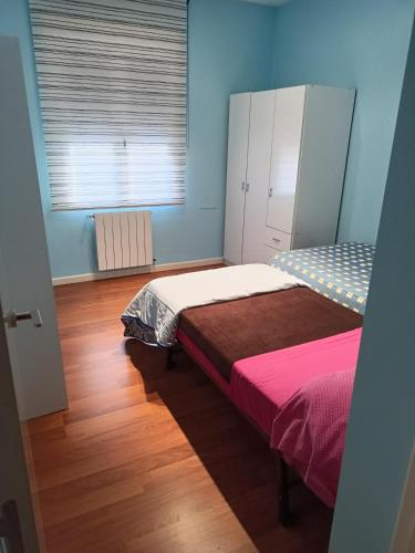 a bedroom with two beds and a window with a radiator at Habitación privada en casa particular in Albacete