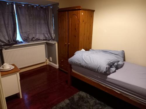 een slaapkamer met een bed, een kast en een raam bij Hall 1 in Farnley