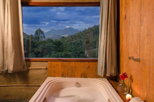 a bath tub in a room with a window at Pousada Lua de Minas in Visconde De Maua