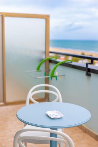 a blue table and two chairs in a room with the ocean at Hotel Continental in Tortoreto Lido