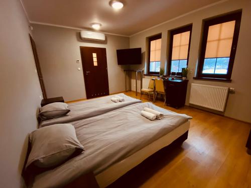 a bedroom with two beds and a desk and windows at Nasz Młyn in Sufczyn