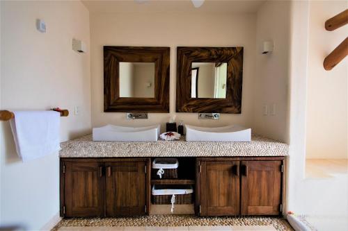 uma casa de banho com dois lavatórios e dois espelhos em Villa Luna Kuku em Zihuatanejo