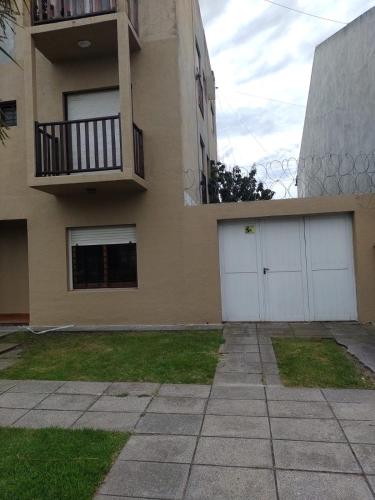un edificio con 2 puertas blancas de garaje y balcón en Departamento Parque Luro para 5 personas en Mar del Plata