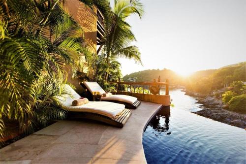 a resort with beds on the side of a river at Villa Peninsula in Zihuatanejo