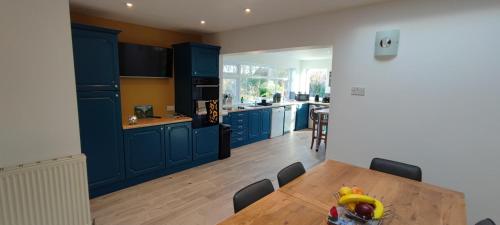 eine Küche mit blauen Schränken und einem Holztisch in der Unterkunft Benllech Sea View bungalow, Dog Friendly sleeps 6 in Benllech