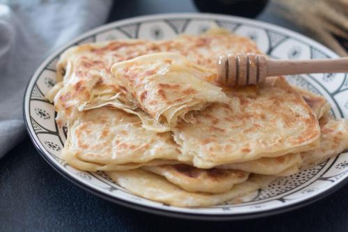 a pile of pancakes on a plate with a fork at Le petit Château des Anges in Marrakech