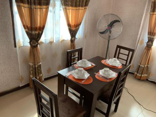 a dining room with a table and chairs and a fan at Executive King 1 Bedroom Apartment in Yaba, Lagos in Lagos