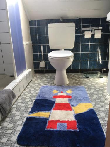 a bathroom with a toilet with a colorful rug on the floor at Gästehaus Mia in Norddeich