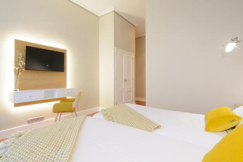 a bedroom with two beds and a tv on the wall at Pazo de Mendoza in Baiona