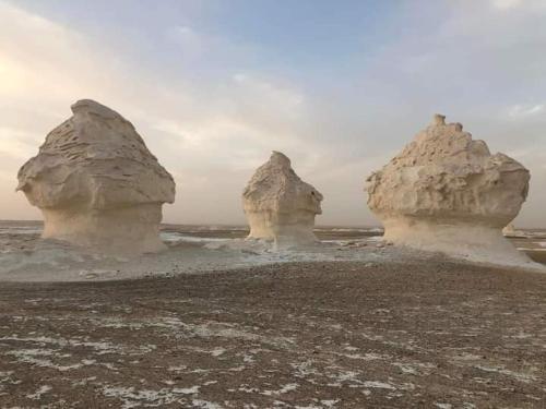 trzy formacje skalne w piasku na plaży w obiekcie Western desert safari w mieście Bawati