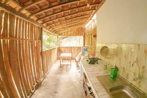 Habitación con paredes de madera y cocina con fregadero. en Villa Kampung Ayem Riverside en Sleman