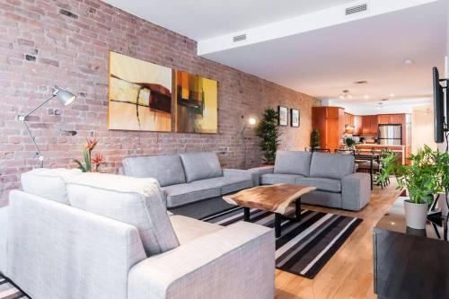 a living room with two couches and a brick wall at Le Metro Mont-Royal by HomeInMontreal in Montréal