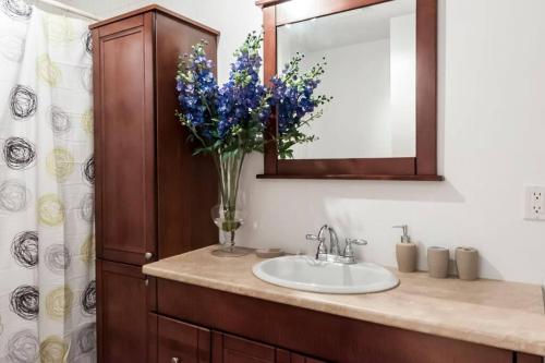 baño con lavabo, espejo y jarrón de flores en Le Metro Mont-Royal by HomeInMontreal, en Montreal