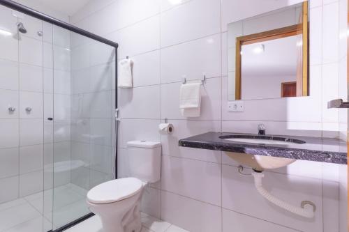 a white bathroom with a toilet and a sink at Pousada Lagoa Azul in Paraty