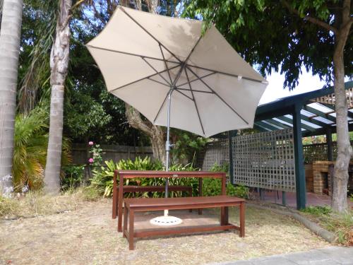 a white umbrella sitting on top of a wooden bench at The Balnarring Motel in Balnarring