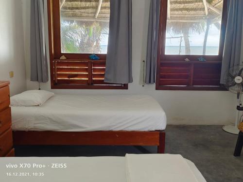 two beds in a room with two windows at Lunazul Eco-Cabaña Frente al Mar in Mahahual