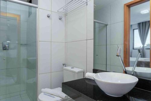 een badkamer met een wastafel, een toilet en een spiegel bij Residence in Barra de São Miguel